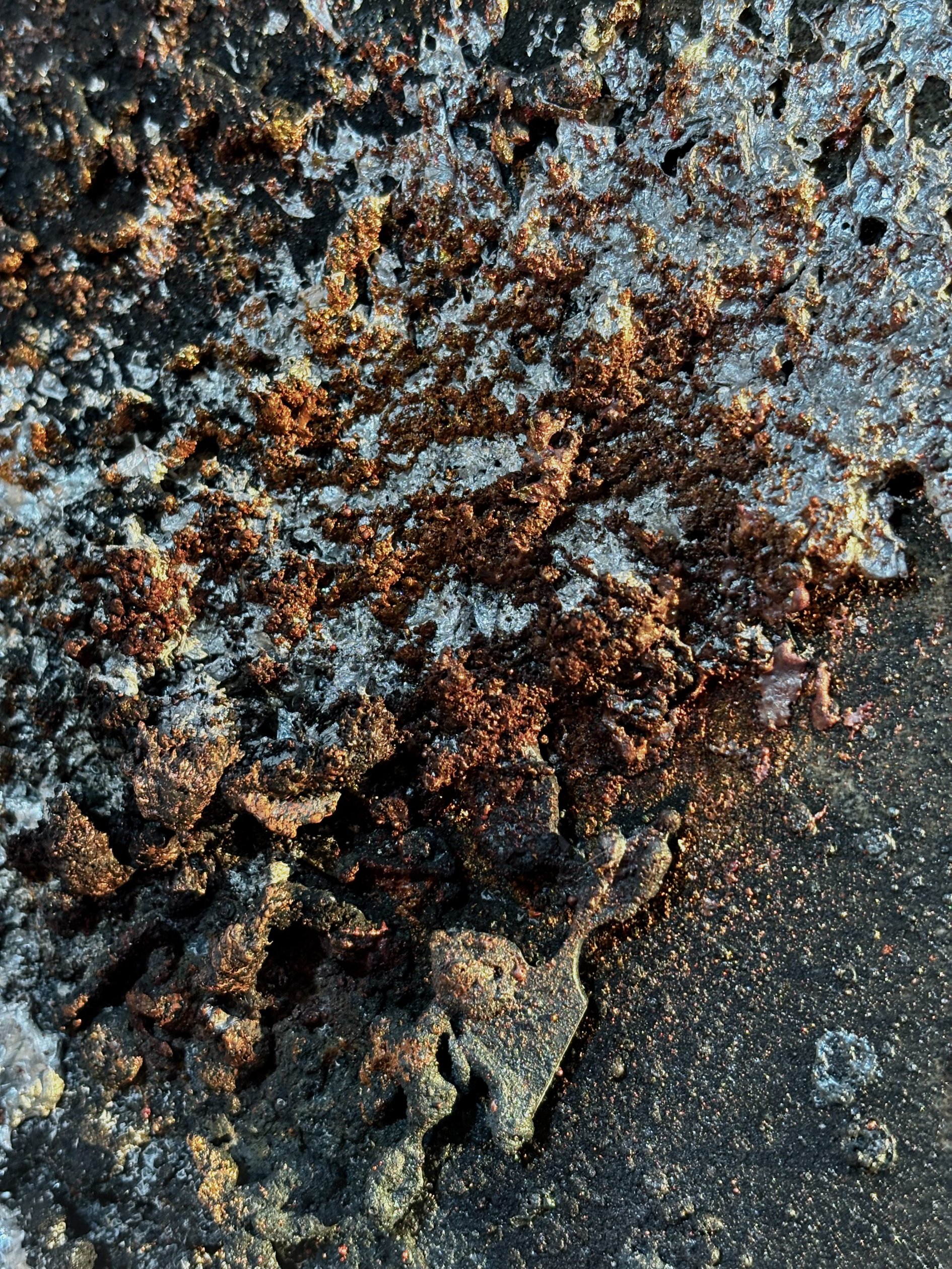 Detail of sprayed metal deposit on speckled mineral tile