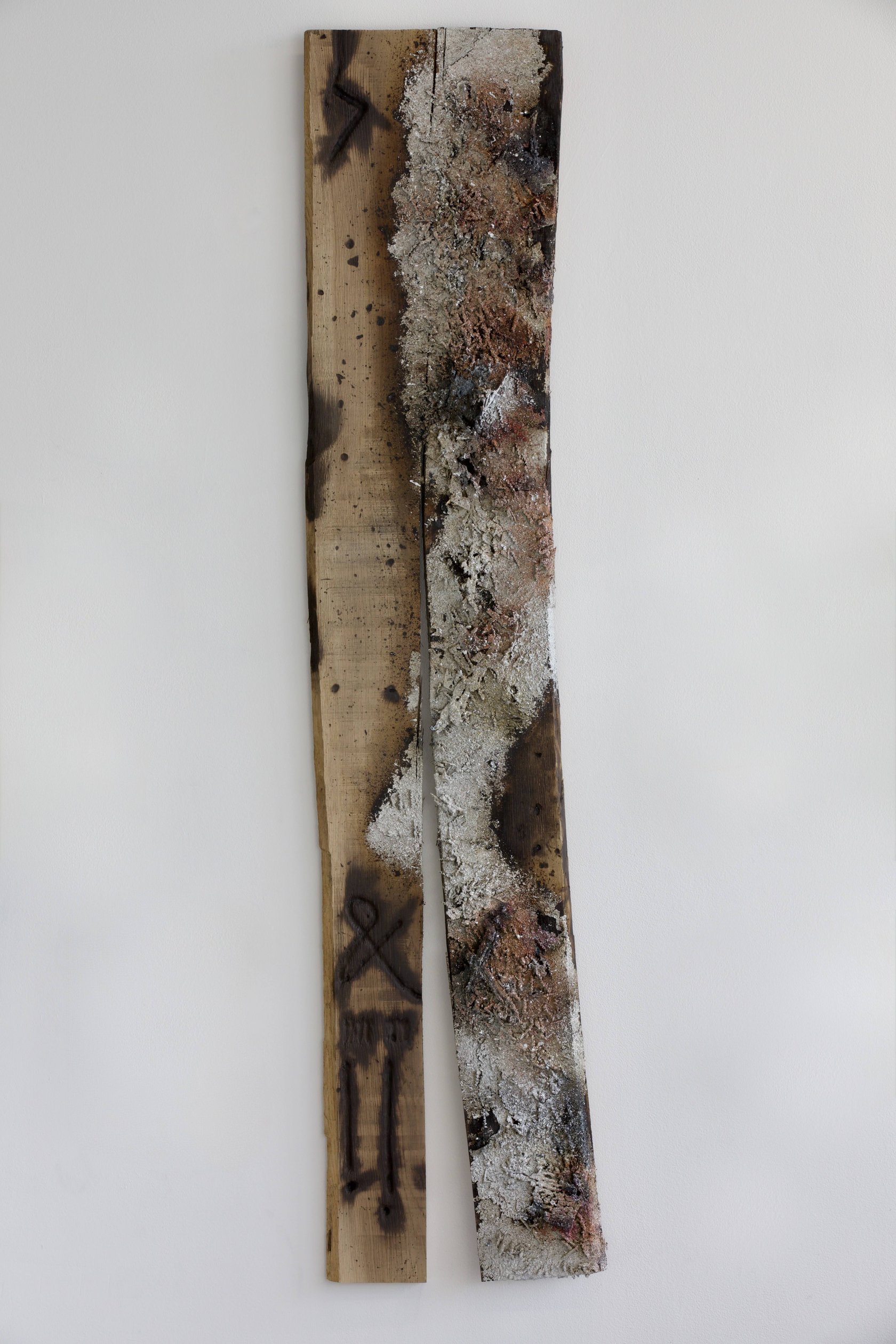 Sprawl: tall wall-mounted oak plank split lengthwise, with sprayed metal residue and burned markings