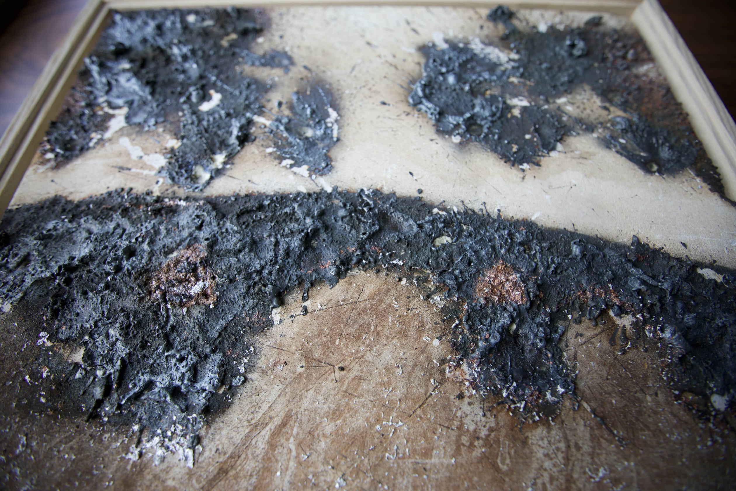 Detail of sprayed metal deposits and cracked mineral tile surface