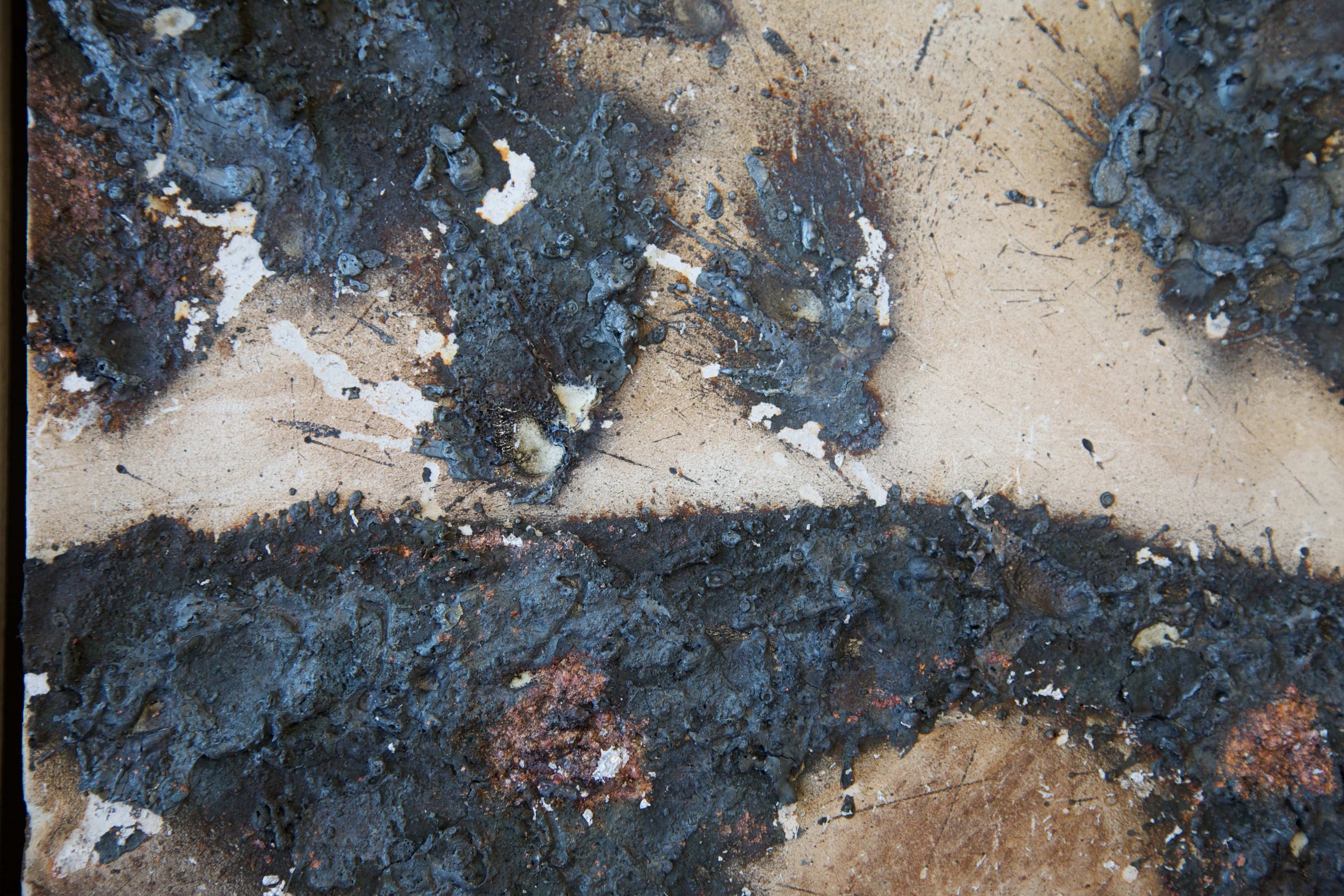 Detail of sprayed metal deposits and cracked mineral tile surface in Dry river