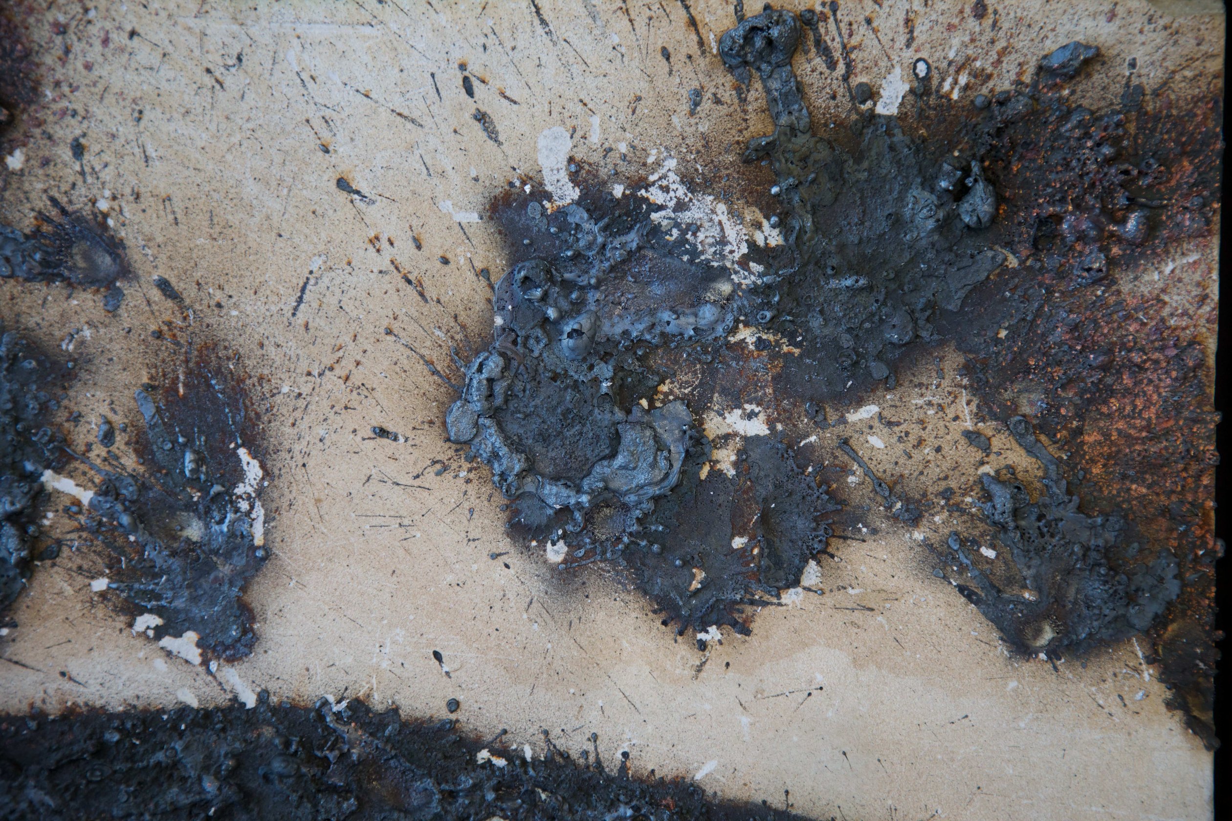 Detail of sprayed metal deposits and cracked mineral tile surface in Dry river